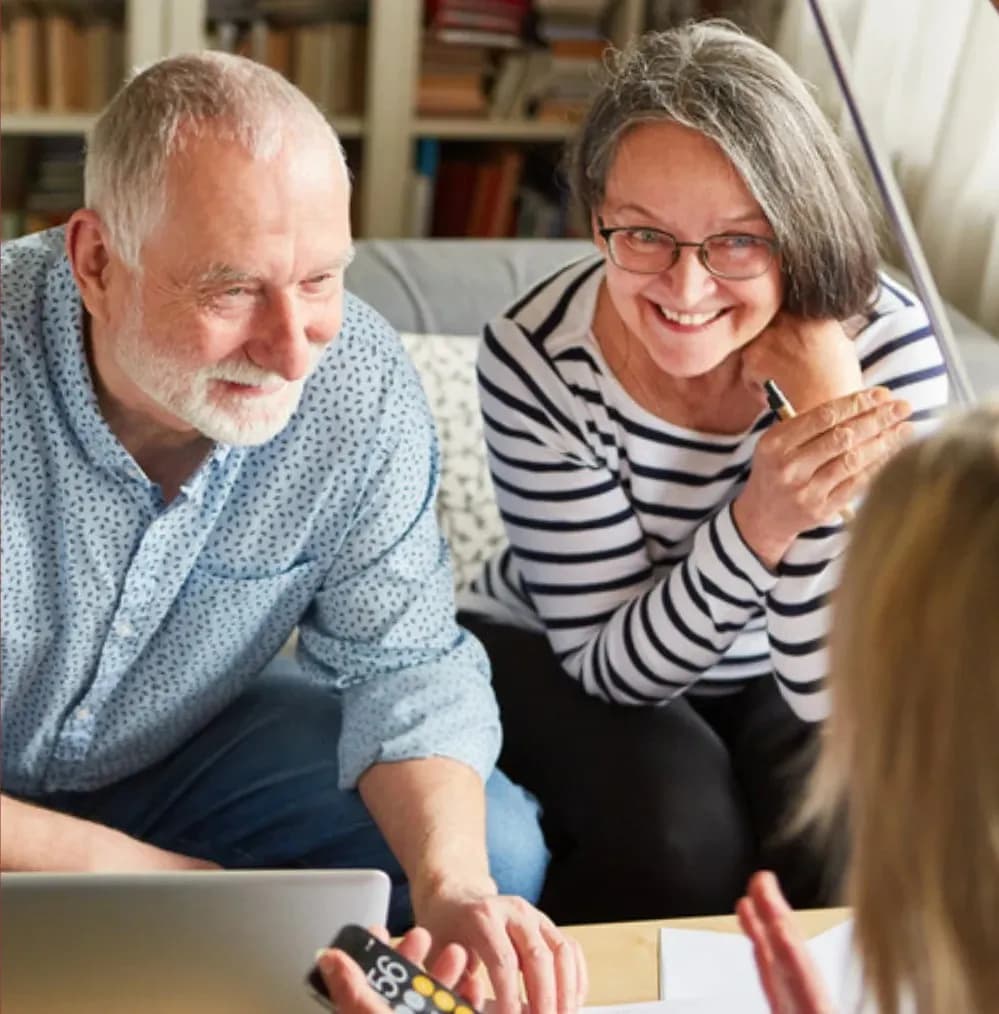 An older couple smiling together as they talk through their plans at home